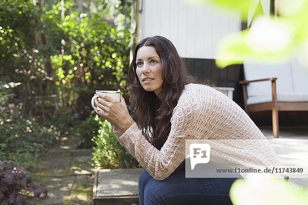Junge Frau trinkt Kaffee auf der Veranda des Chalets