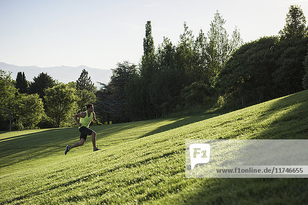 Young man doing training run on hill in park