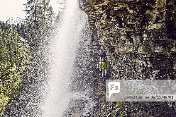 Junges Paar geht unter einem Wasserfall hindurch  Tirol  Österreich