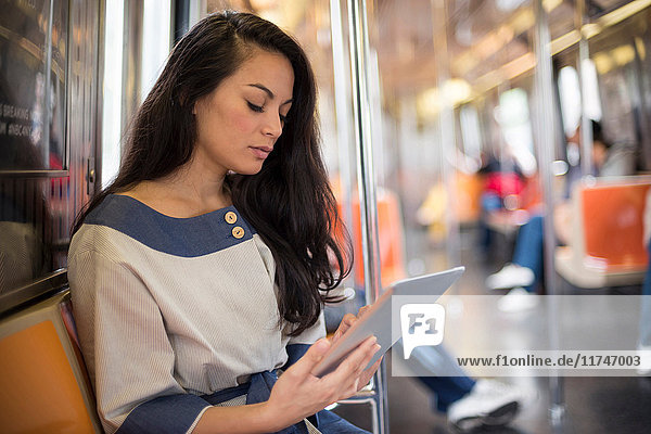 Mittelgroße erwachsene Frauen mit digitalem Tablet in der U-Bahn  New York