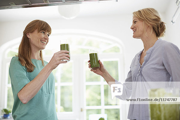 Frauen trinken grünen veganen Smoothie in der Küche