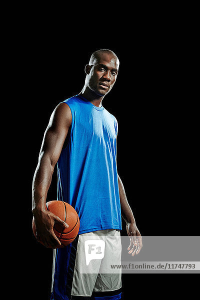 Studioporträt eines Basketballspielers mit Ball