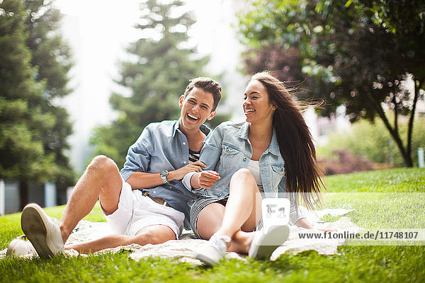 Young couple sitting in park  laughing