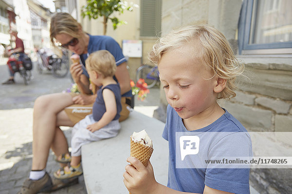 Mutter und Söhne sitzen draußen und essen Eiscreme
