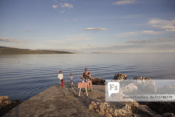 Mutter und zwei Söhne picknicken an der Küste  Krk  Kroatien