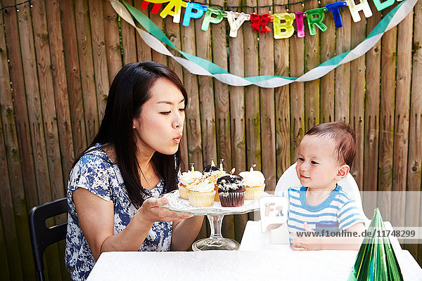 Mother blowing out candles on baby boy's birthday cakes