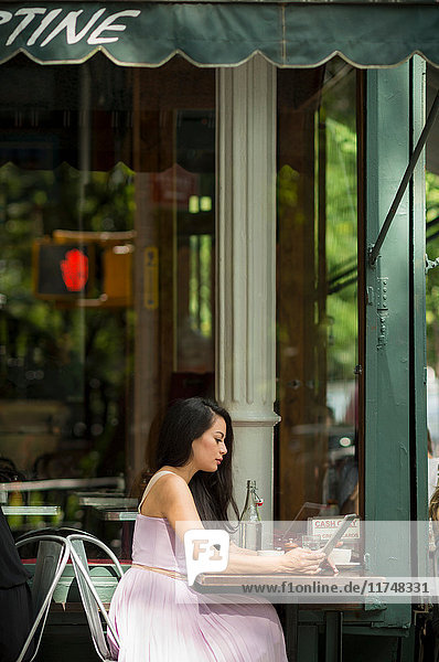 Mittelgroße erwachsene Frauen mit digitalem Tablet im Straßencafé
