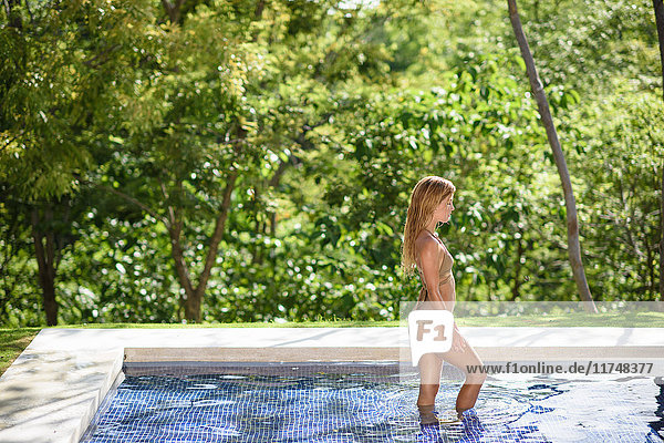 Young woman wearing gold bikini in swimming pool
