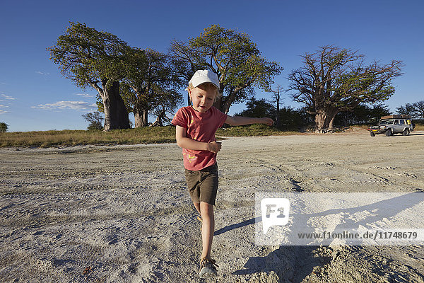 Junge spielt auf Schotterstraße  Nxai-Pan-Nationalpark  Kalahari-Wüste  Afrika