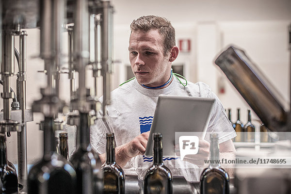 Young man working with digital tablet in bottling plant