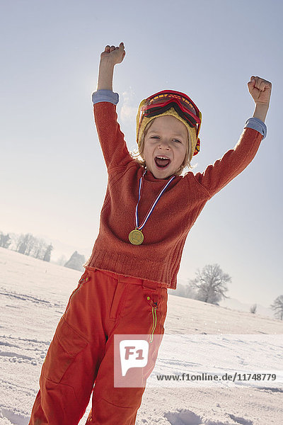 Young boy with medal around neck  celebrating with arms raised