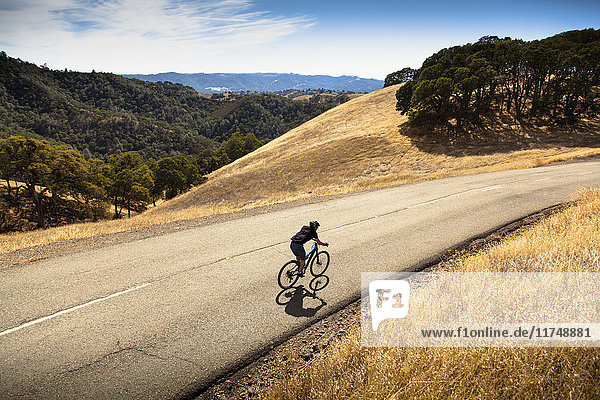 Erhöhte Ansicht eines jungen Mannes beim Mountainbiken auf einer Landstraße  Mount Diablo  Bay Area  Kalifornien  USA