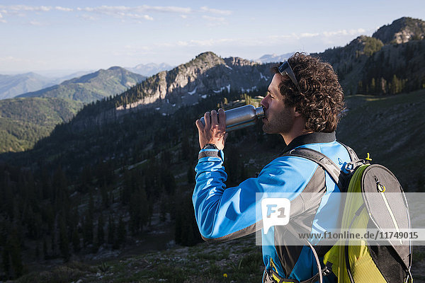 Hiker taking break  drinking  Sunset Peak trail  Catherine's Pass  Wasatch Mountains  Utah  USA