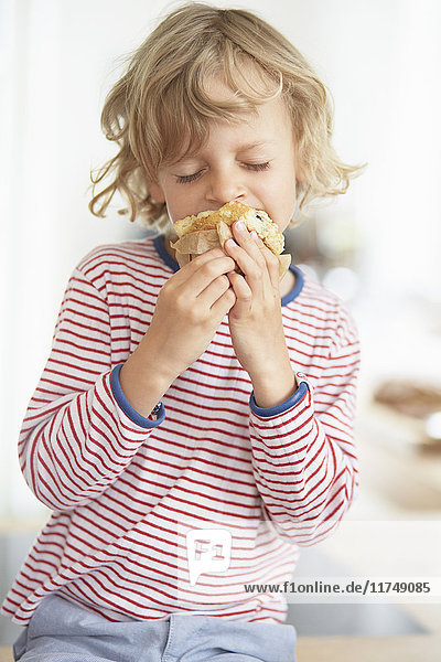 Young boy eating muffin