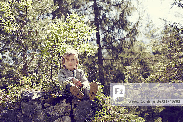 Young boy relaxing on rocks in forest
