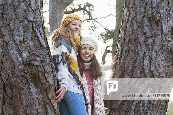 Porträt von Mädchen im Teenager-Alter  die in einem Baum stehen und lächelnd in die Kamera schauen