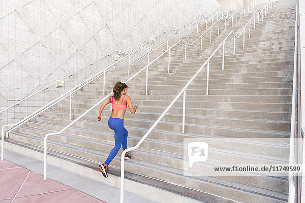Rückansicht einer jungen Frau in Sportkleidung beim Treppensteigen