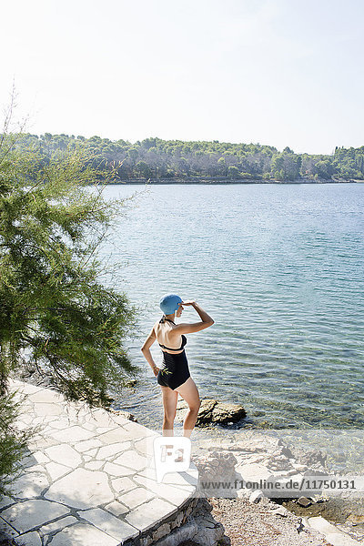 Rear view of young woman wearing swimming costume gazing out to sea  Milna  Brac  Croatia