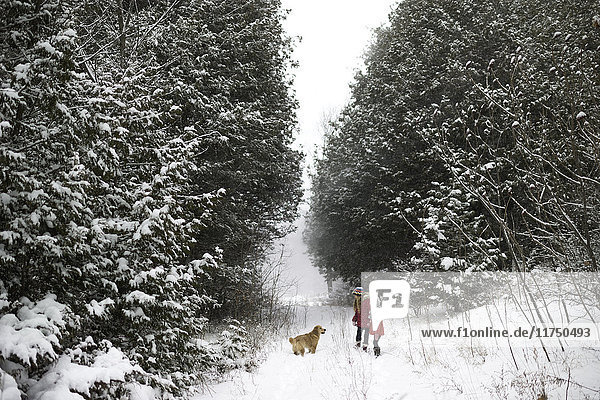 Schwestern erkunden verschneiten Wald mit Hund