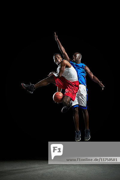 Männliche Basketballspieler springen und schießen Ball