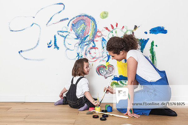 Mutter und Tochter zeichnen auf weisse Wand