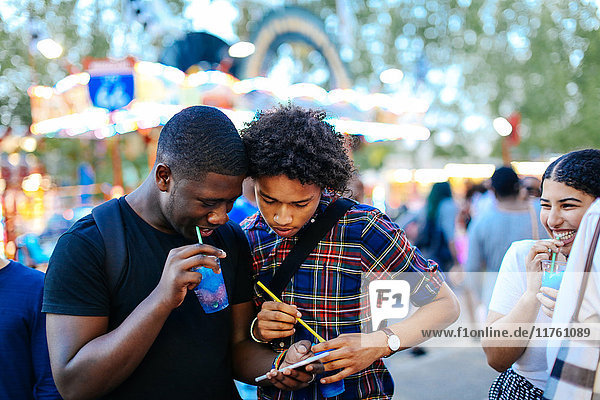 Group of friends at funfair  two boys looking at smartphone