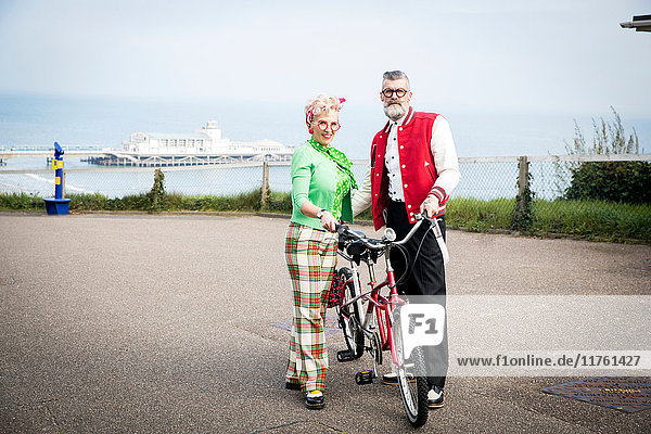 Portrait of 1950's vintage style couple with tandem bicycle at coast