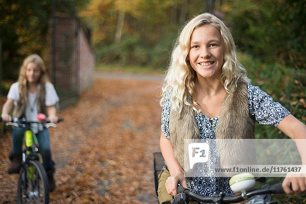Porträt von zwei Schwestern beim Radfahren im Herbstpark