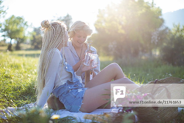 Junges Paar auf Picknickdecke im Feld mit Weinflasche und Gläsern  Mallorca  Spanien