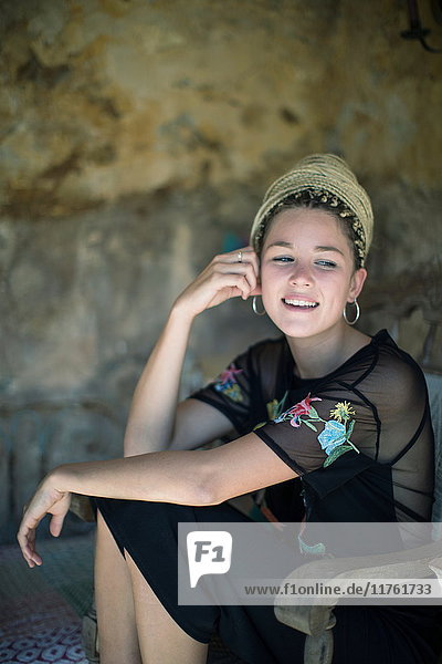 Porträt einer jungen Frau mit Dreadlocks  die im Freien sitzt und lächelt