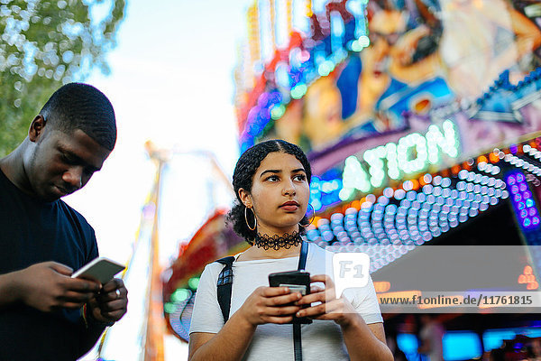 Zwei Freunde auf dem Jahrmarkt mit Smartphones in der Hand