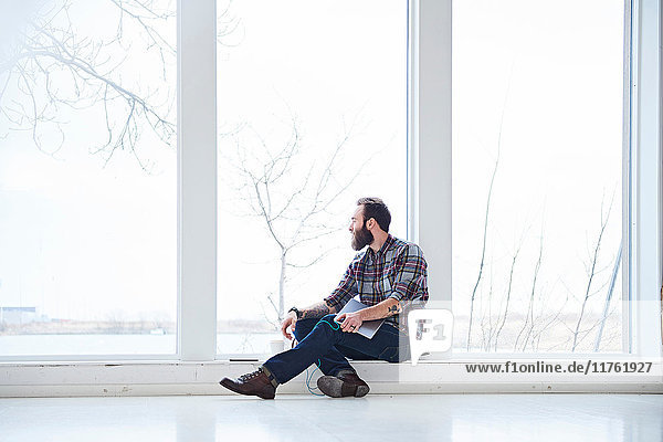 Junger männlicher Designer schaut vom Fenster des Designstudios durch das Fenster