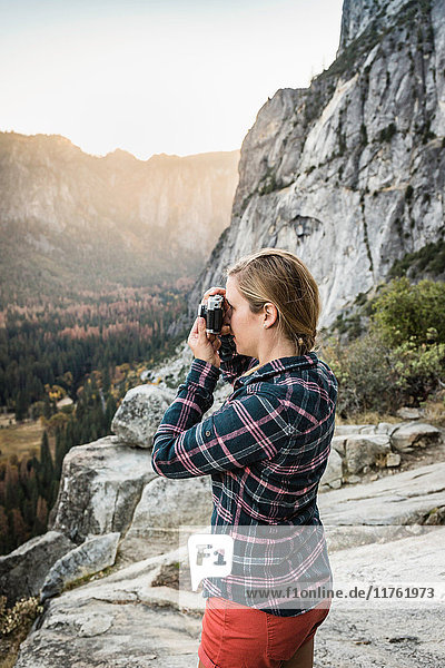Woman photographing landscape from rock formation  Yosemite National Park  California  USA
