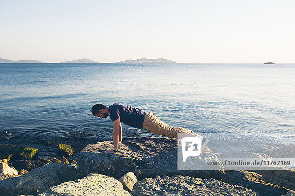 Mann macht Push-Ups auf Felsen auf dem Meer  Istanbul  Türkei