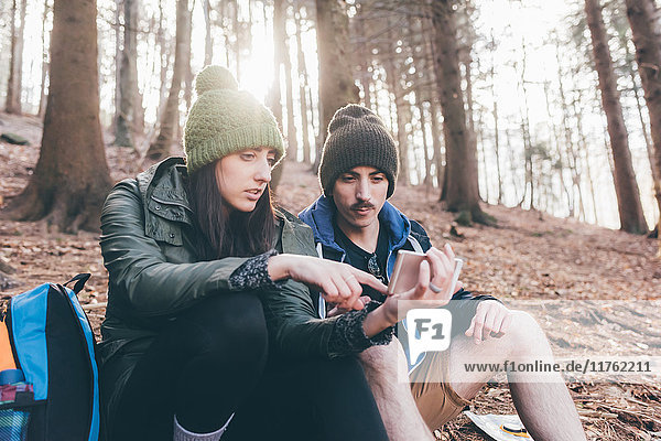 Wanderndes Ehepaar im Wald beim Blick auf das Smartphone  Monte San Primo  Italien