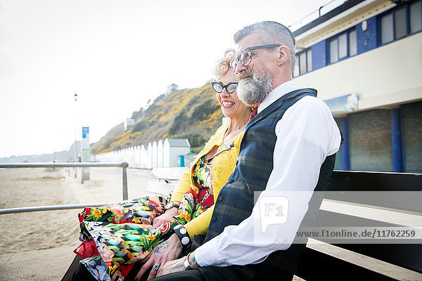Ehepaar im Vintage-Stil der 1950er Jahre  das von der Strandbank aus den Blick auf sich zieht