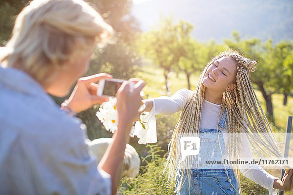 Junger Mann fotografiert Freundin im Feld mit Wildblumen  Mallorca  Spanien
