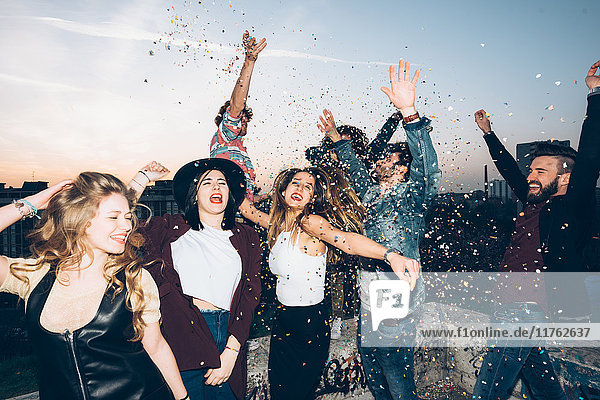 Group of friends dancing  enjoying roof party  confetti in air