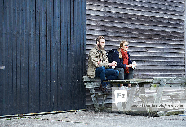 Designer und Designerinnen sitzen auf einer Bank vor dem Designstudio