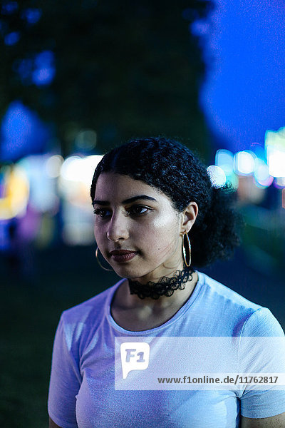 Portrait of teenage girl at funfair at night