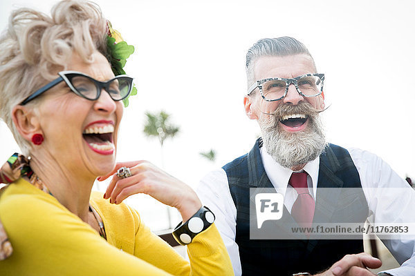Ehepaar aus den 1950er Jahren im Vintage-Stil lacht gemeinsam an der Küste