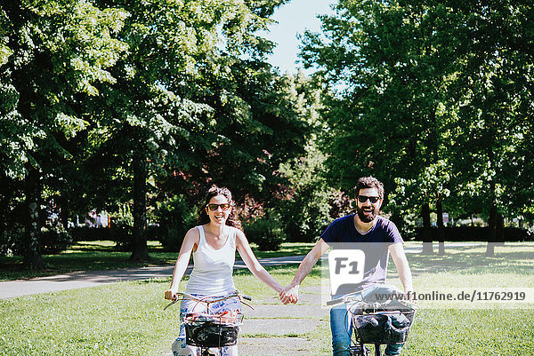 Paar hält beim Radfahren im Park Händchen  Arezzo  Toskana  Italien