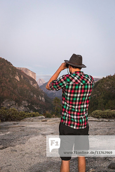 Rear view of man looking through binoculars Yosemite National Park California USA