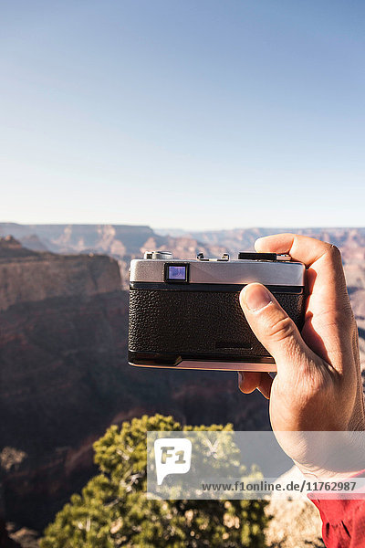 Man's hand holding camera photographing Grand Canyon National Park Arizona USA