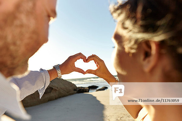Ein reifes Paar  steht am Strand und formt mit vereinten Händen sein Herz  Kapstadt  Südafrika