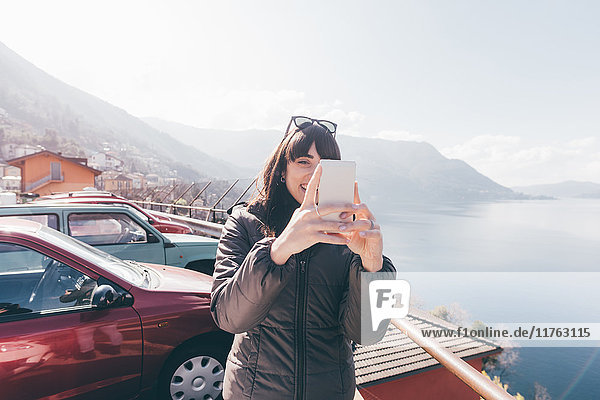 Mittelgroße erwachsene Frau mit Smartphone-Selfie am Seeufer  Monte San Primo  Italien