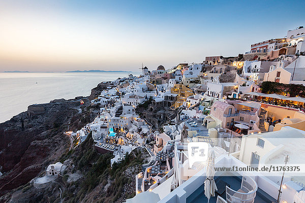 Blick bei Sonnenuntergang auf die weiß getünchten Gebäude und Windmühlen von Oia  Santorin  Kykladen  Griechische Inseln  Griechenland  Europa