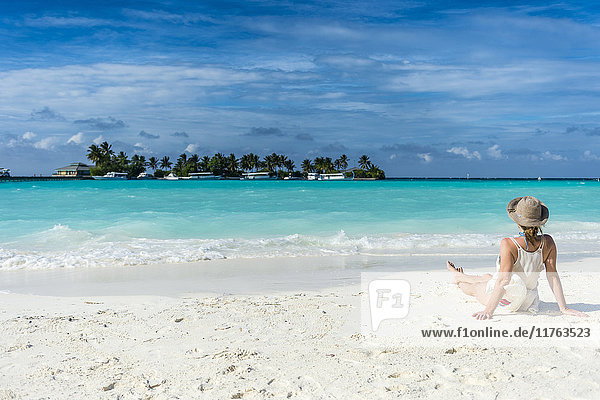 Woman sitting on a white sand beach enjoying the turquoise water  Sun Island Resort  Nalaguraidhoo island  Ari atoll  Maldives  Indian Ocean  Asia