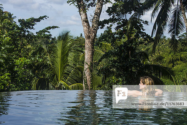 Frau genießt einen überlaufenden Pool oberhalb eines Tals im Kamandalu Ubud Resort  Ubud  Bali  Indonesien  Südostasien  Asien