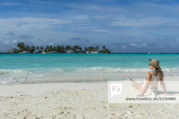 Woman sitting on a white sand beach enjoying the turquoise water  Sun Island Resort  Nalaguraidhoo island  Ari atoll  Maldives  Indian Ocean  Asia